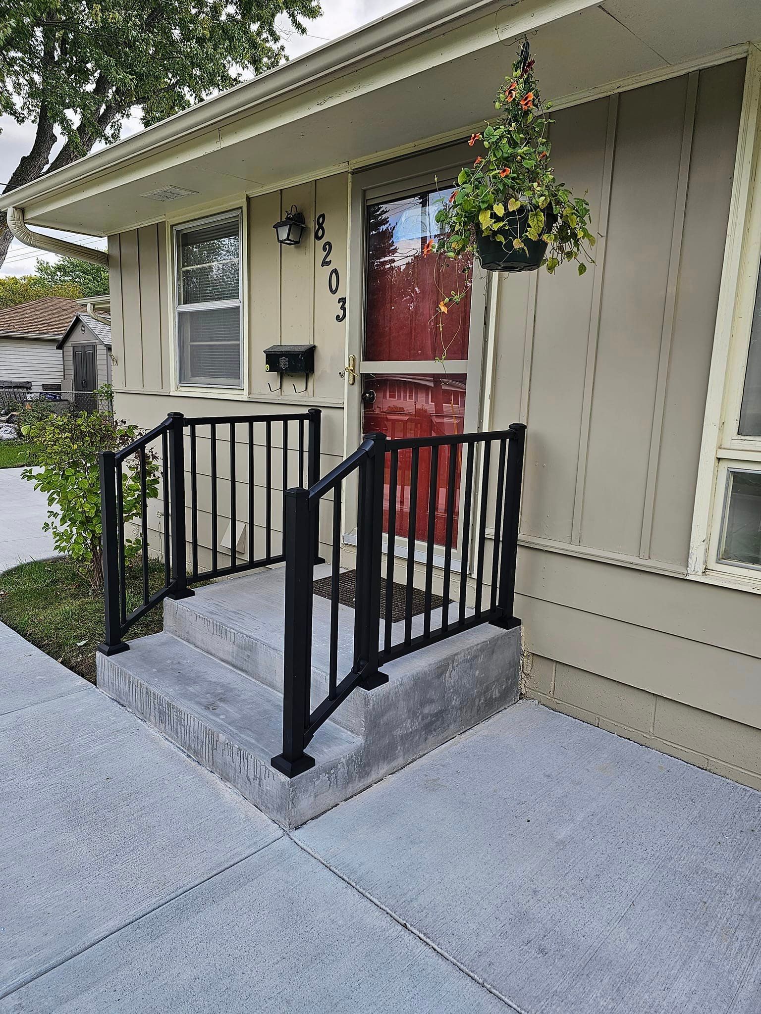 A house with a black railing and a red door