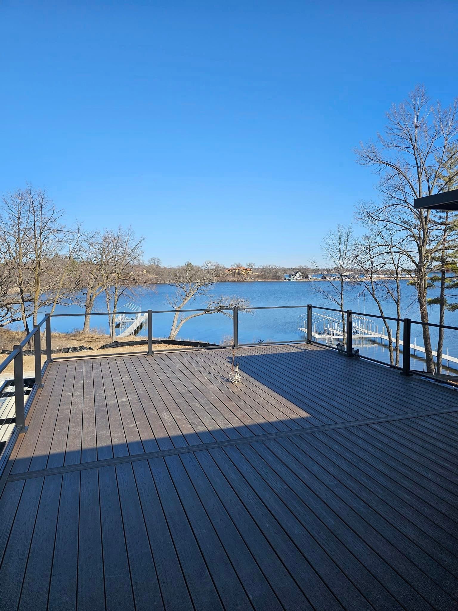 A wooden deck overlooking a lake on a sunny day.
