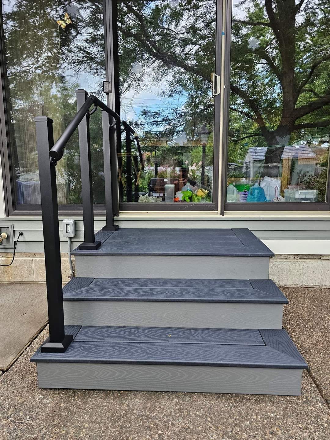 A set of stairs leading up to a house with a black railing.