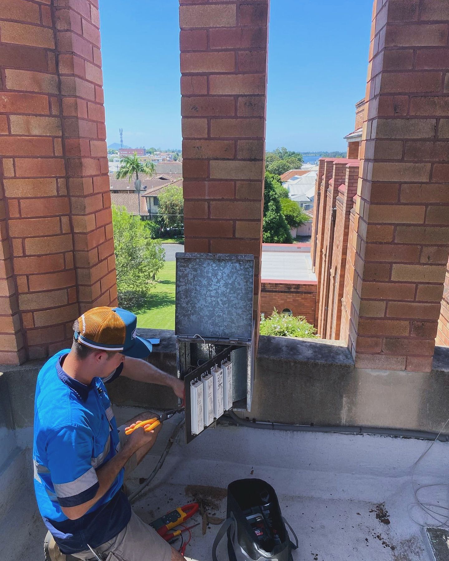 A Man is Sitting on a Balcony Working on a Electric Supply — J T Walker Electrical In Forster - Tuncurry, NSW