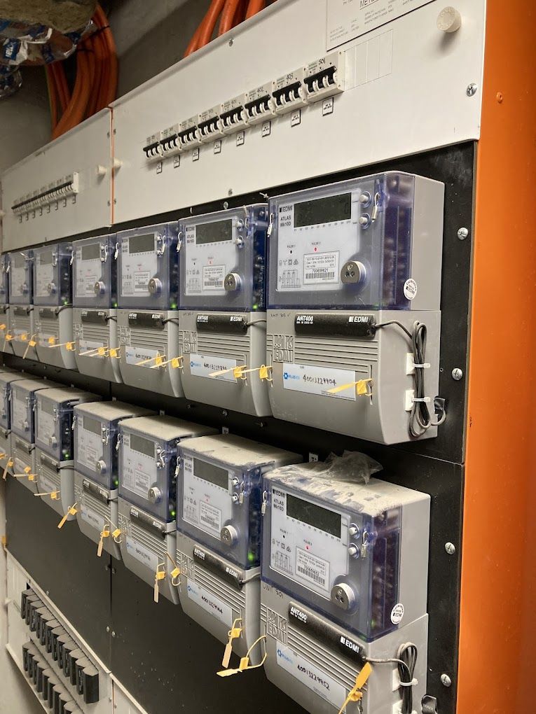Electric meters mounted on a panel, with circuit breakers above.