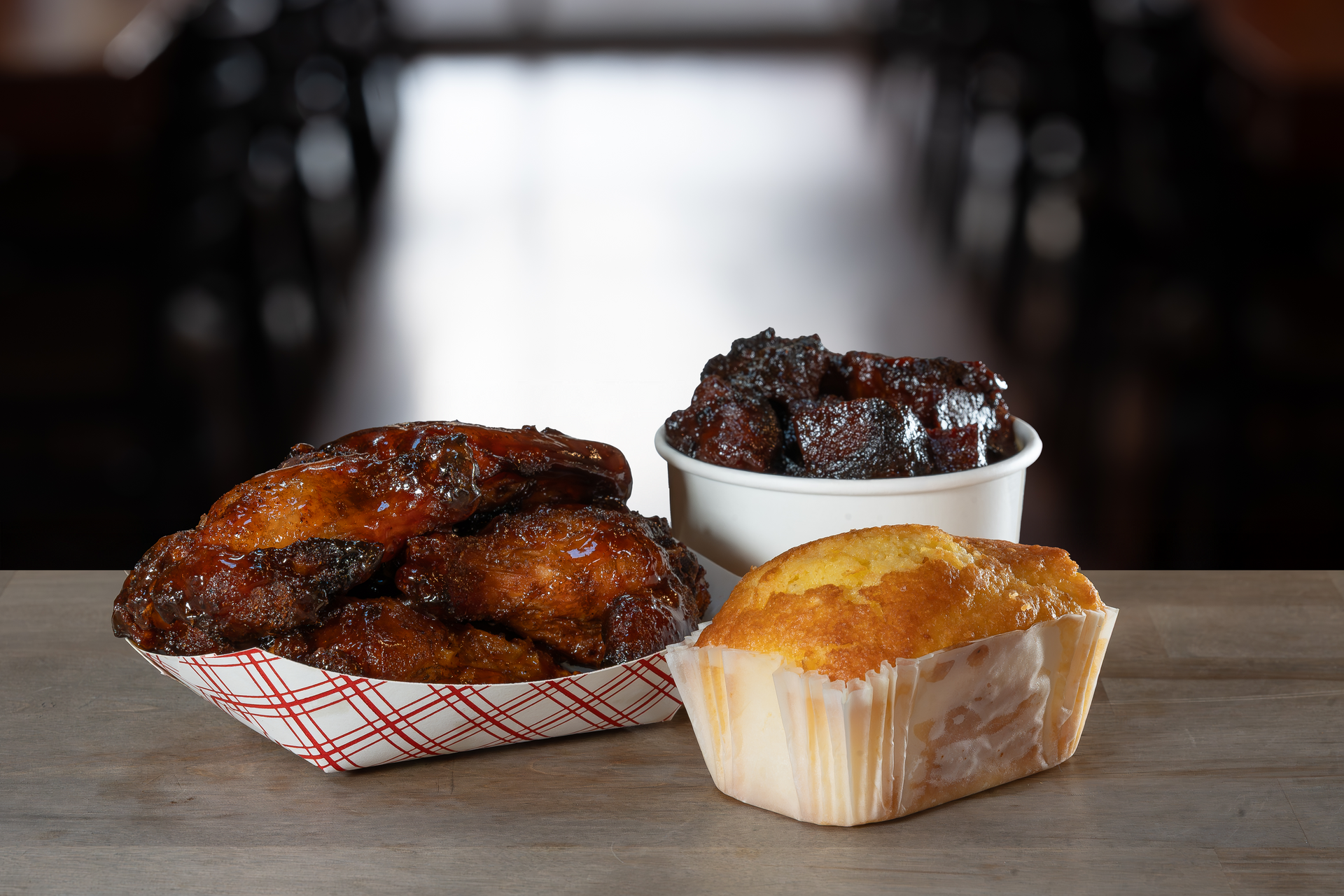 Barbecue food: wings, burnt ends, and a slice of cake on a table.