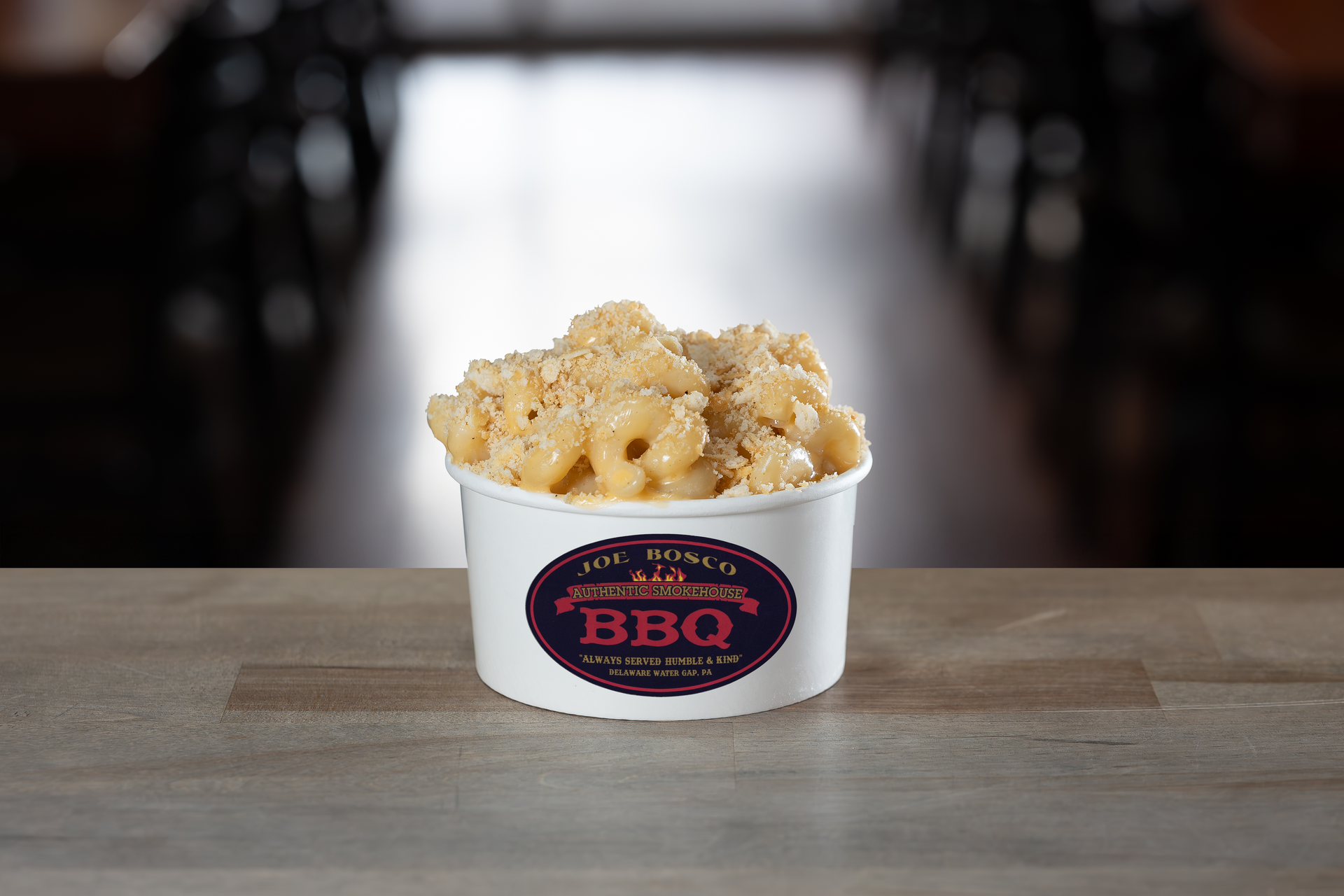 Mac and cheese in a white paper cup with a Joe Bosco BBQ sticker