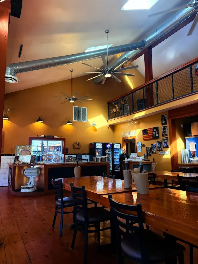 Interior of a restaurant with wooden tables, high ceilings, exposed ductwork, and a mezzanine.