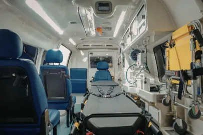 Interior of an ambulance. A stretcher is in the center, flanked by seats and medical equipment.