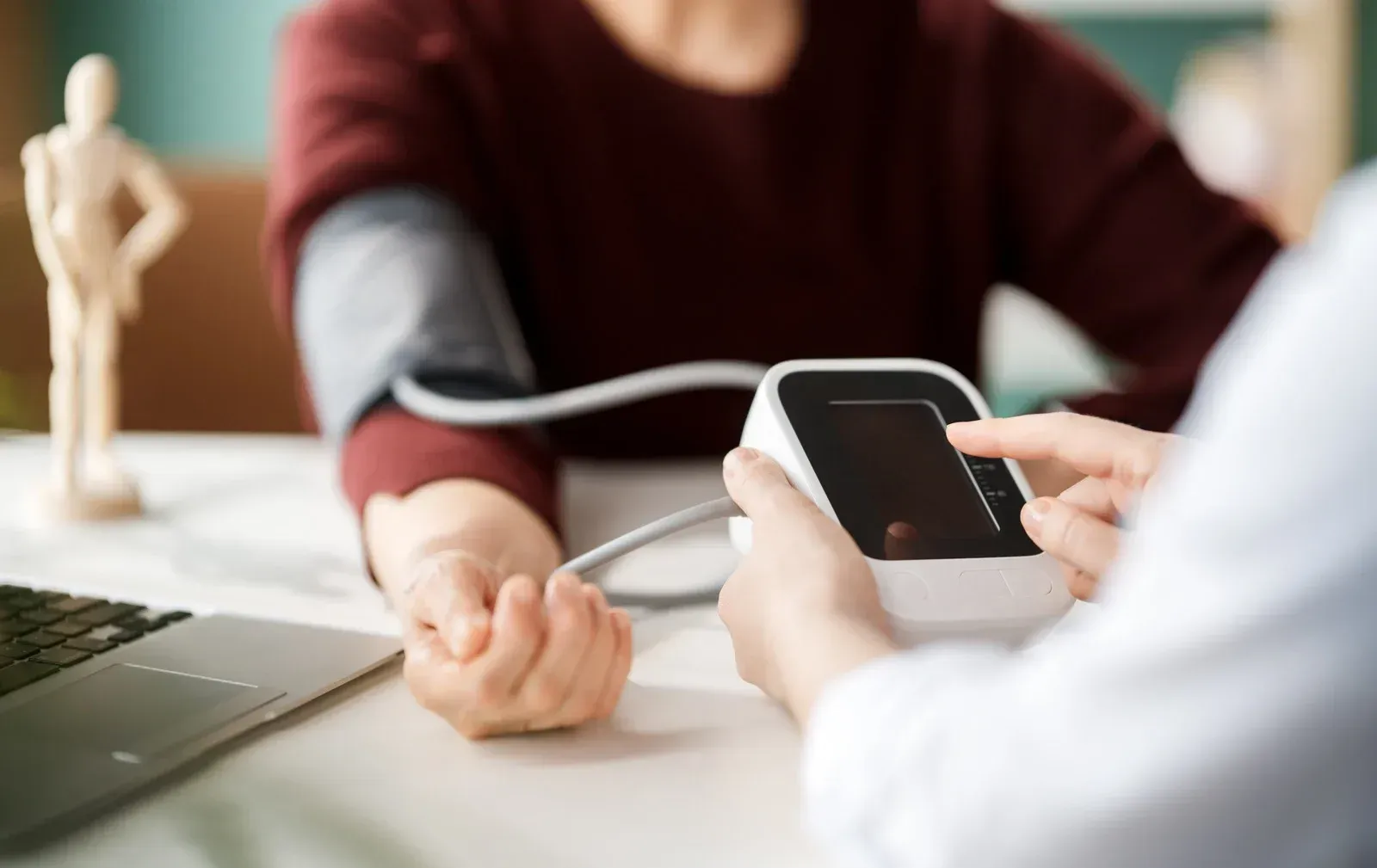Doctor taking patient's blood pressure with an electronic monitor in an office setting.