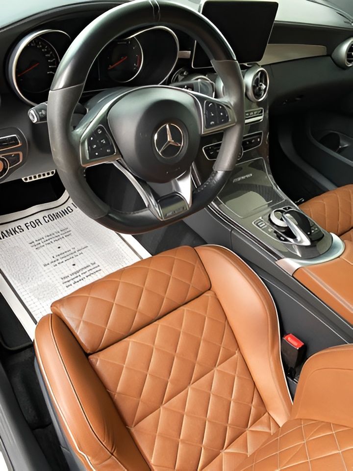 Interior of a Mercedes-Benz with brown diamond-stitched leather seats and black steering wheel.