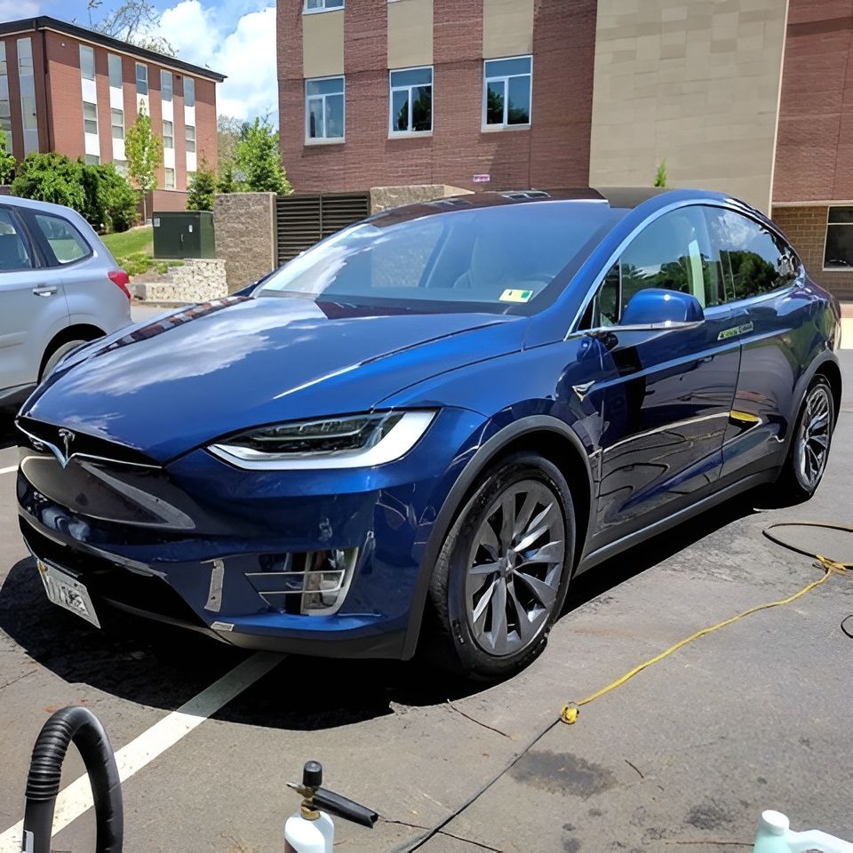 Blue Tesla Model X parked outdoors, next to another car.