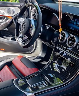 Mercedes-Benz car interior with a red leather seat, a glossy black dashboard, and a chrome steering wheel.