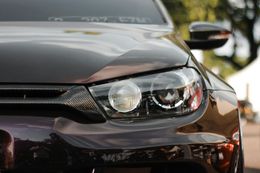 Close-up of a dark purple car's front, showing headlights and carbon fiber trim.