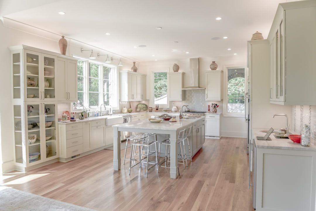 a large kitchen with white cabinets and hardwood floors and a large island in the middle .