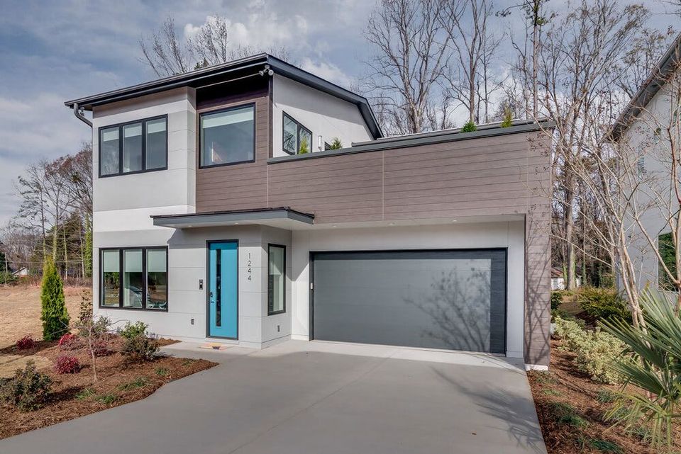 a modern house with a blue door and a gray garage door .