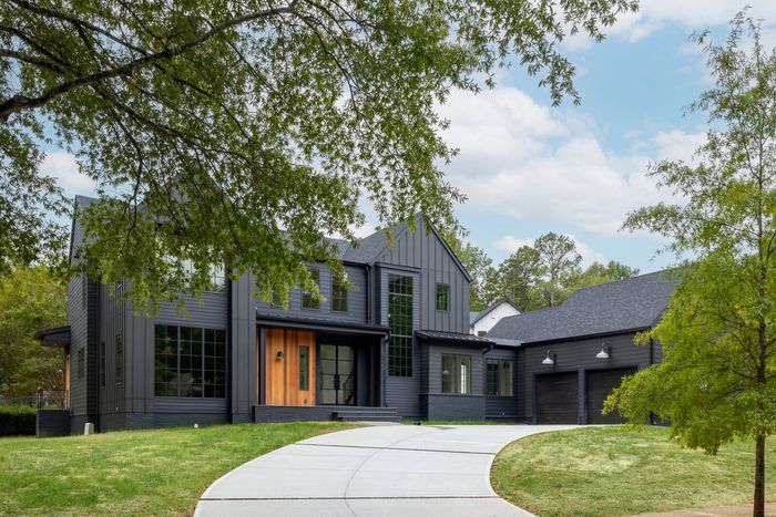 a dark gray house with natural wood siding and driveway