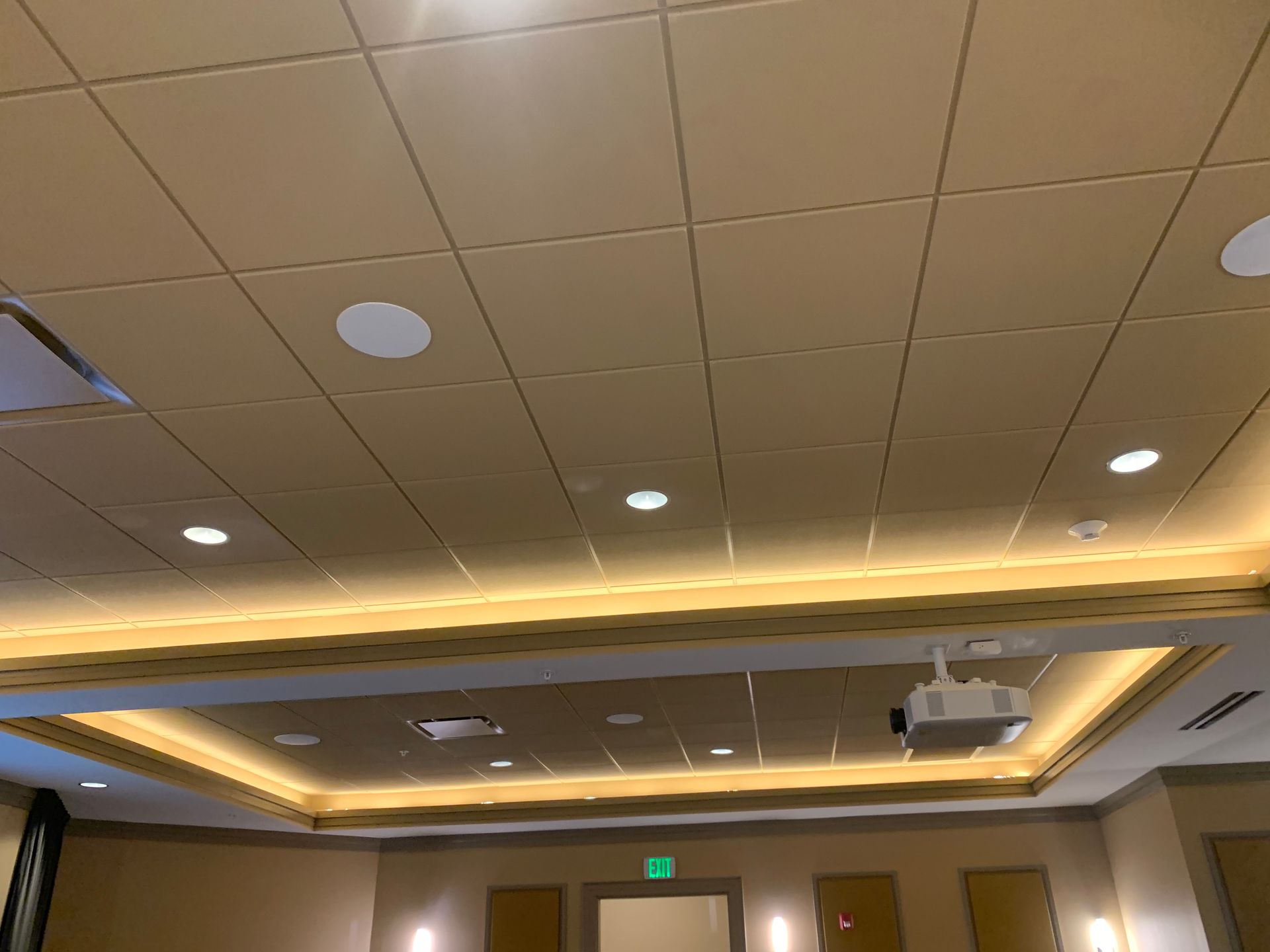 Conference room ceiling with recessed lights, projector, and warm cove lighting