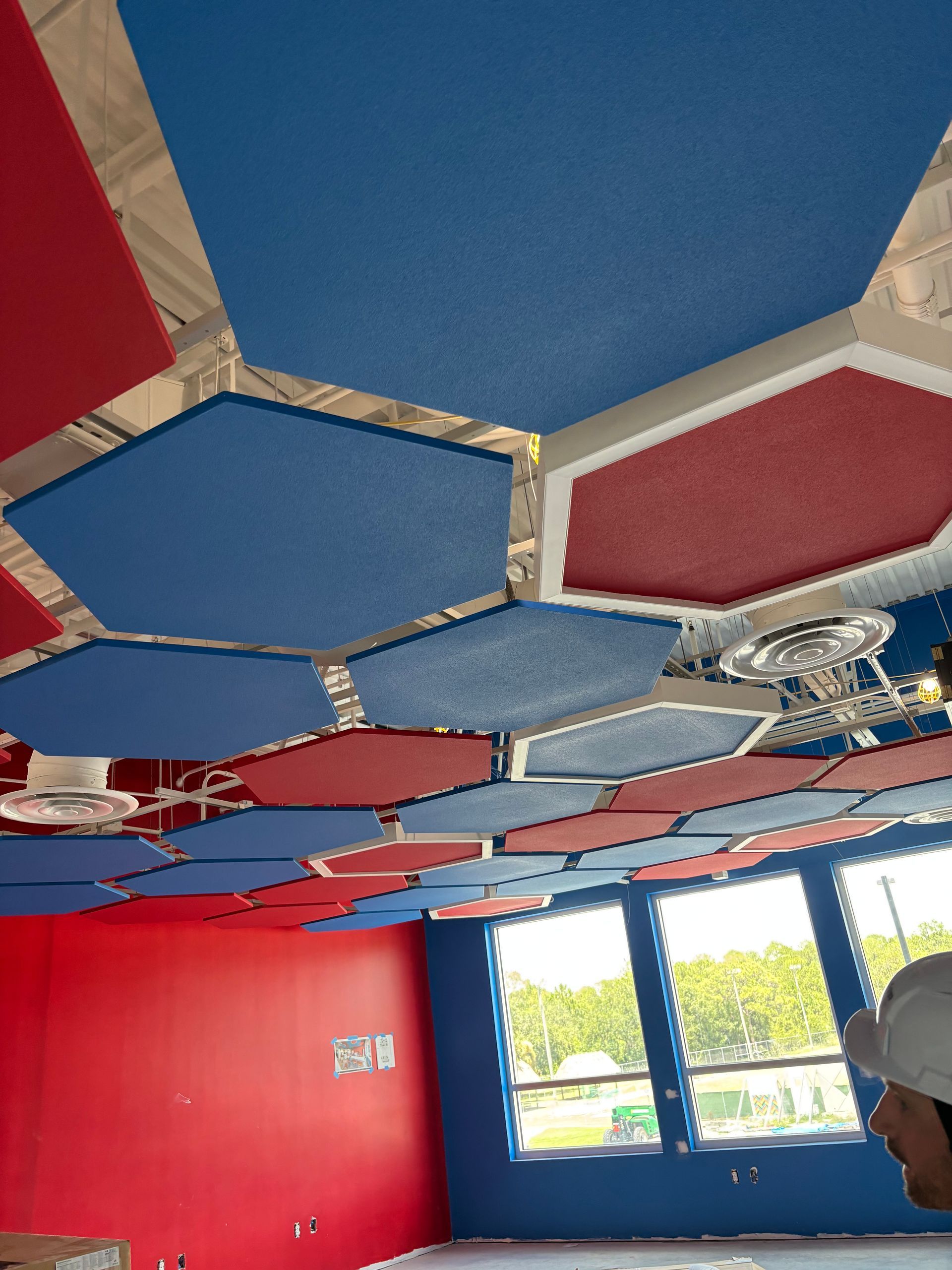 Colorful hexagonal ceiling panels in a room with red and blue walls and windows.