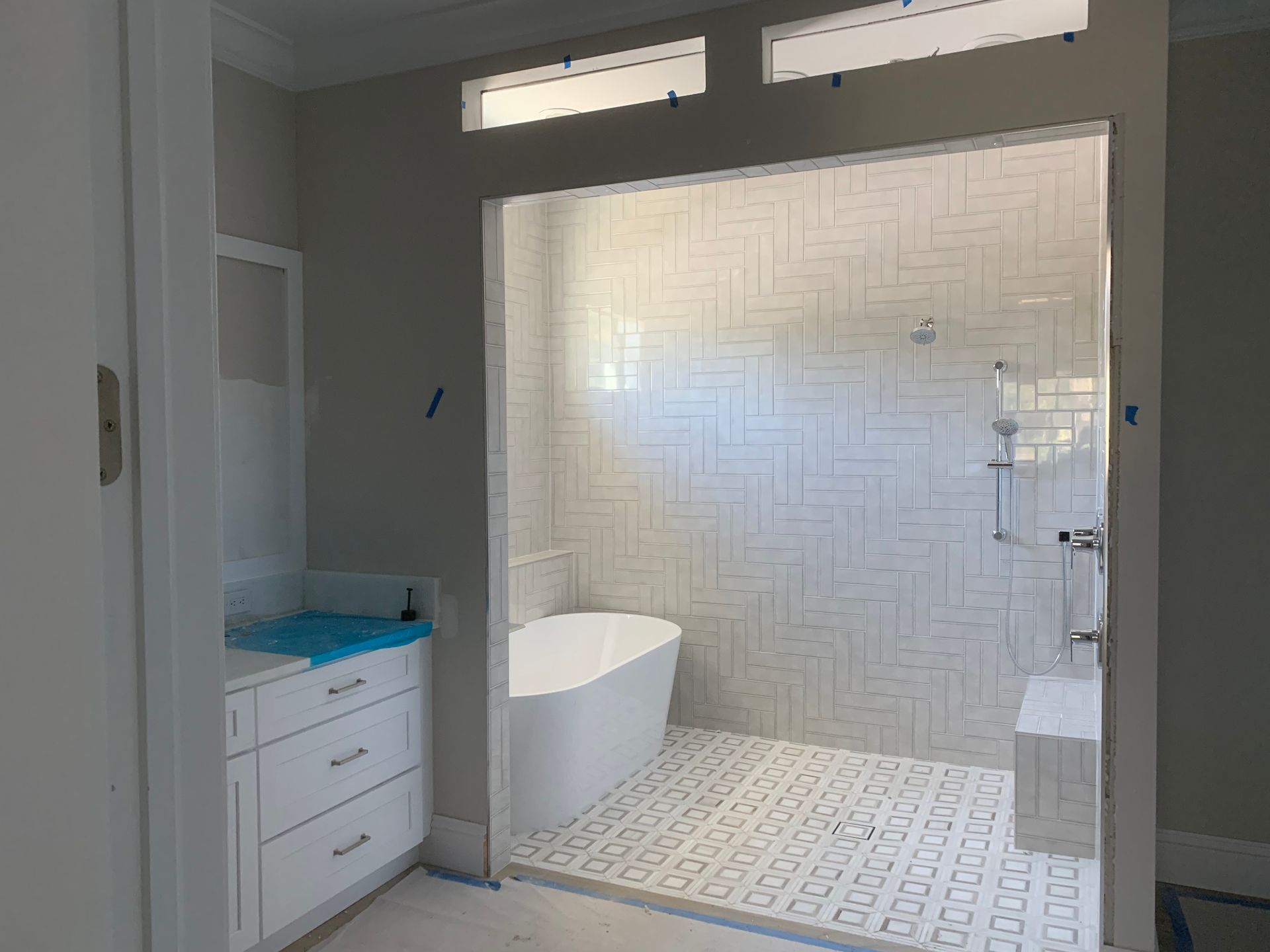 Bright modern bathroom with white tile, double vanity, and freestanding tub inside a shower area