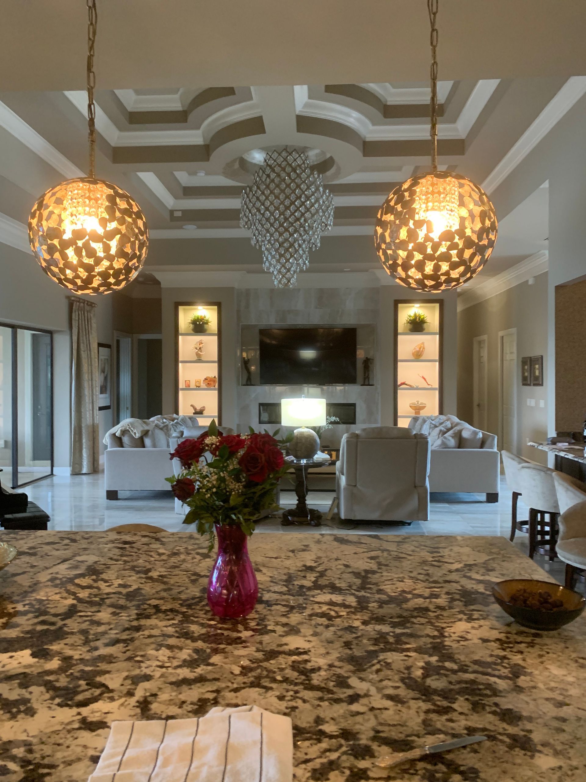 Elegant living room with marble island, chandelier lights, and a floral centerpiece