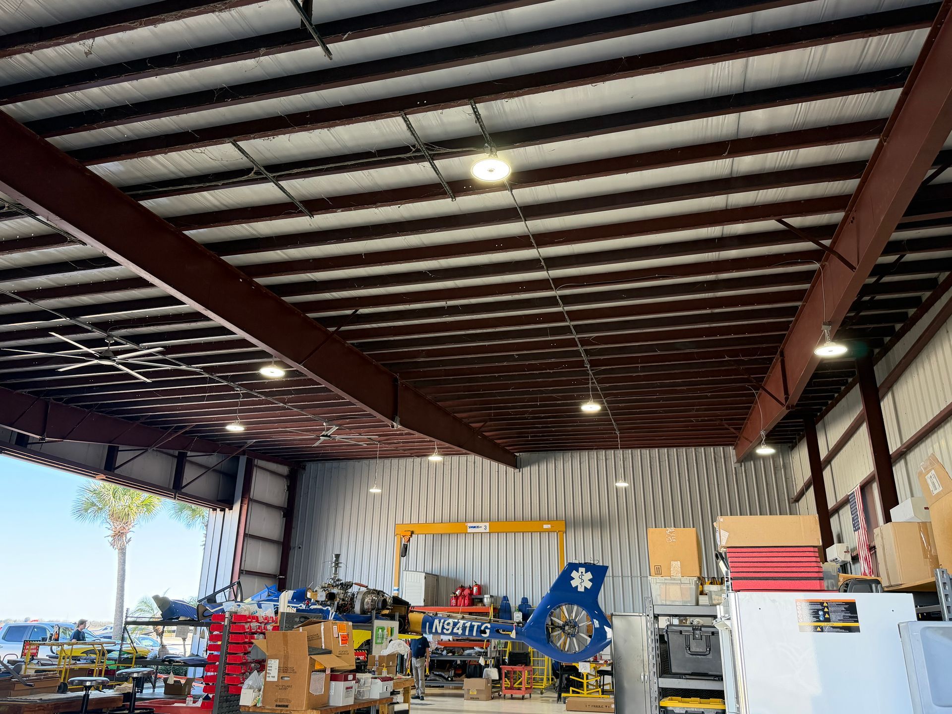 Inside a warehouse workshop with tools, equipment, and a partially open bay door showing daylight.