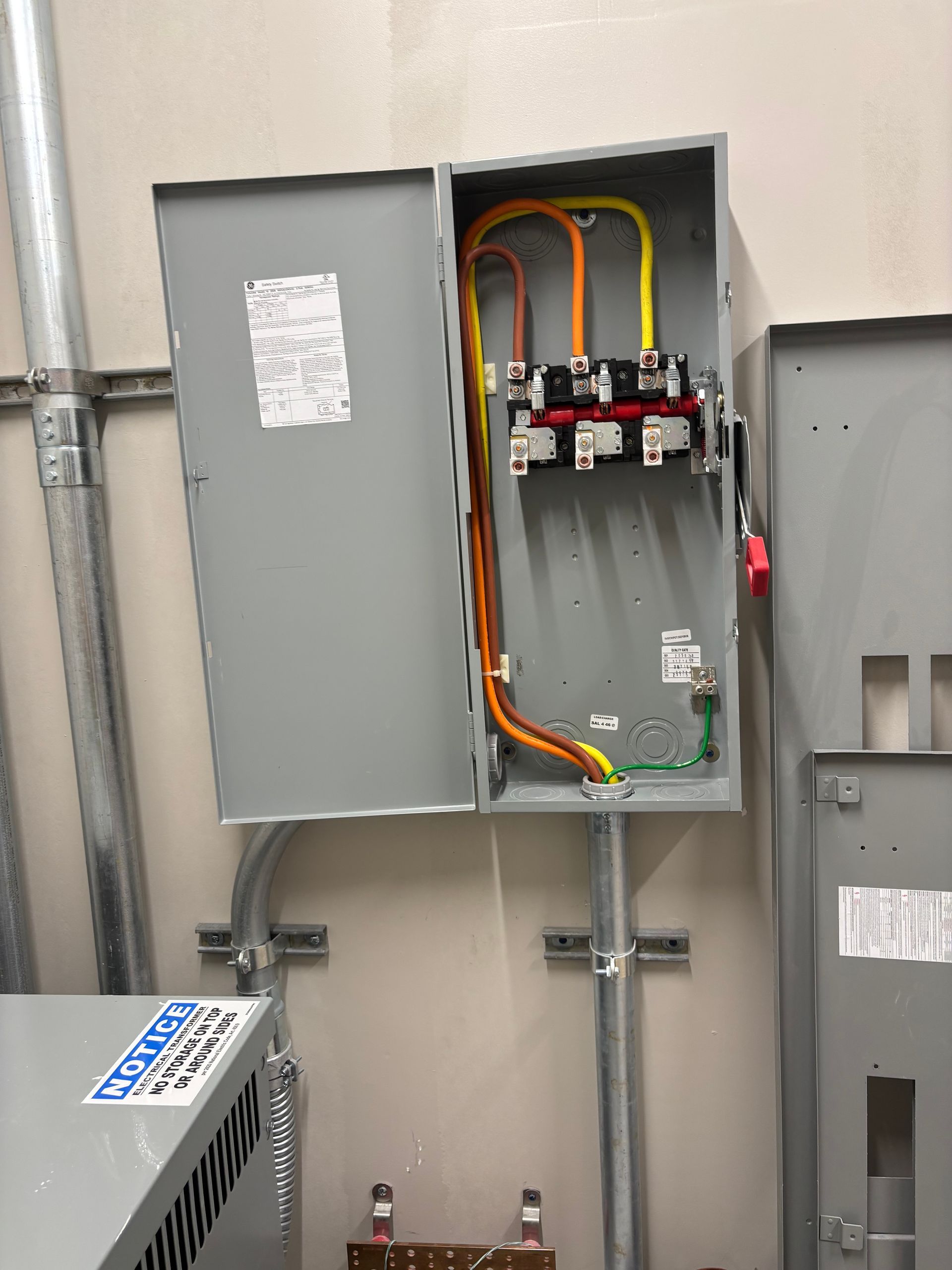 Open electrical panel with wires and breakers in a utility room