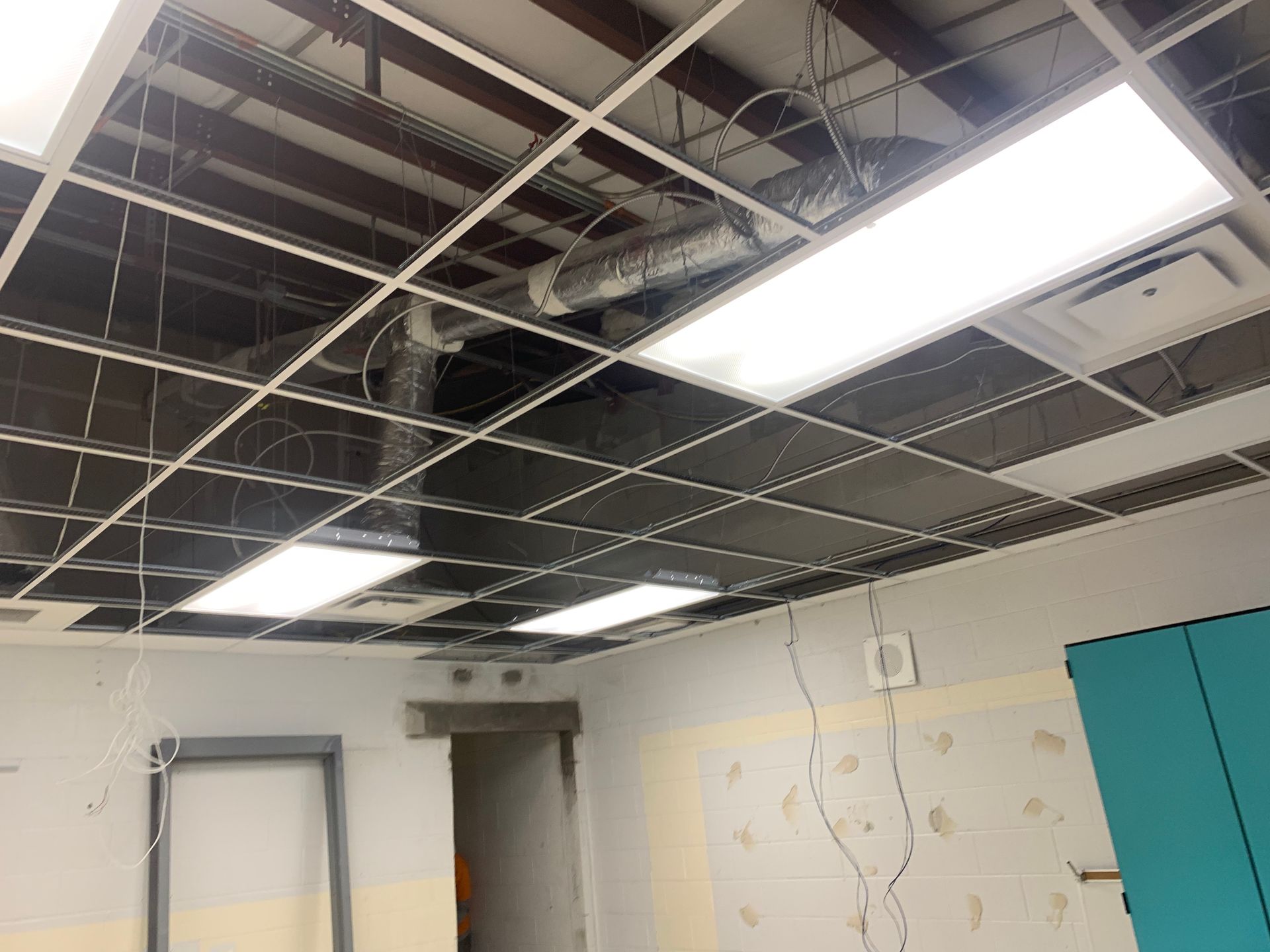 Partially installed ceiling grid with fluorescent lights in a room under renovation