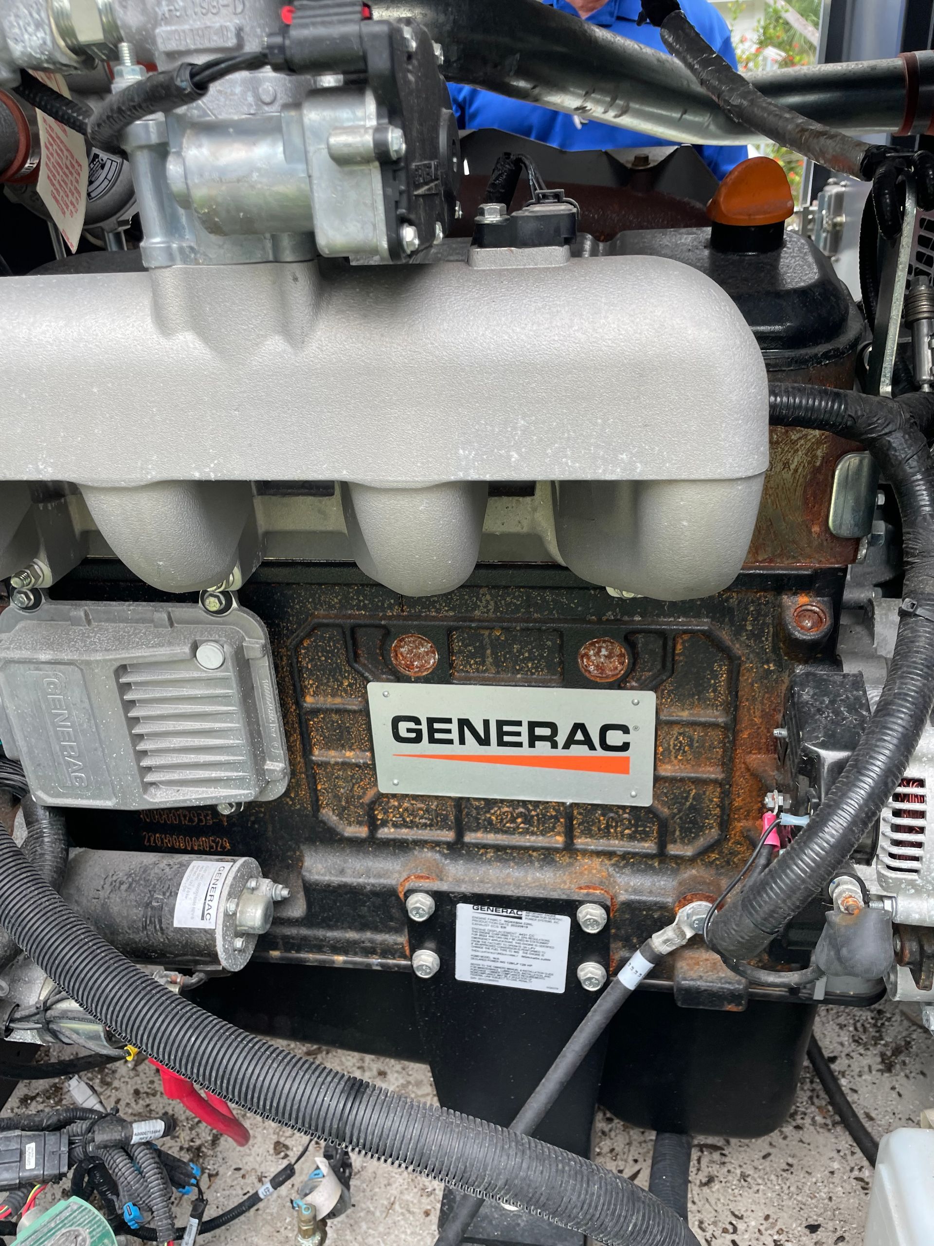 Generac generator engine with white intake manifold and orange rust spots in a tight engine compartment