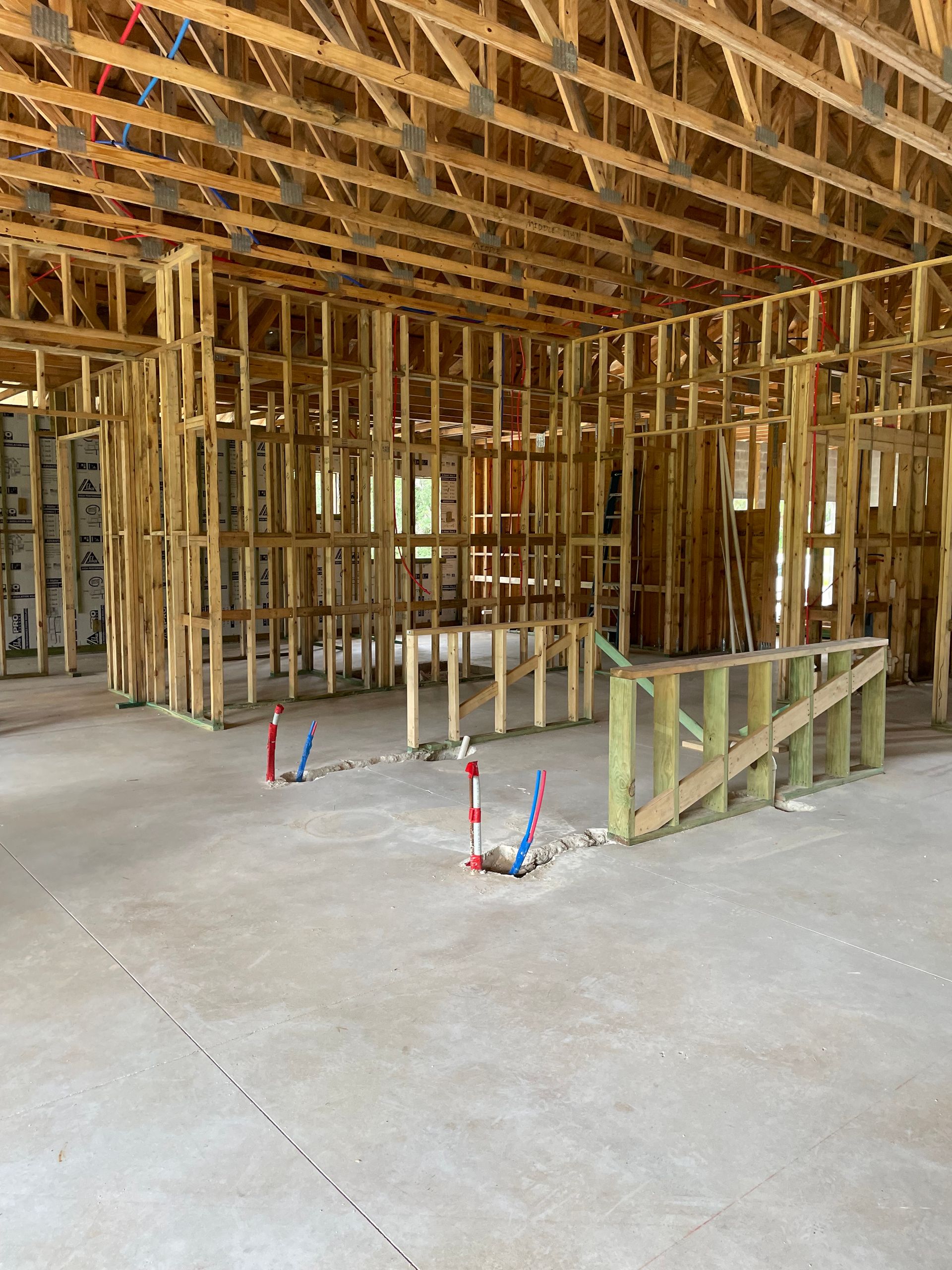 Framed house interior under construction with exposed wooden studs and concrete floor