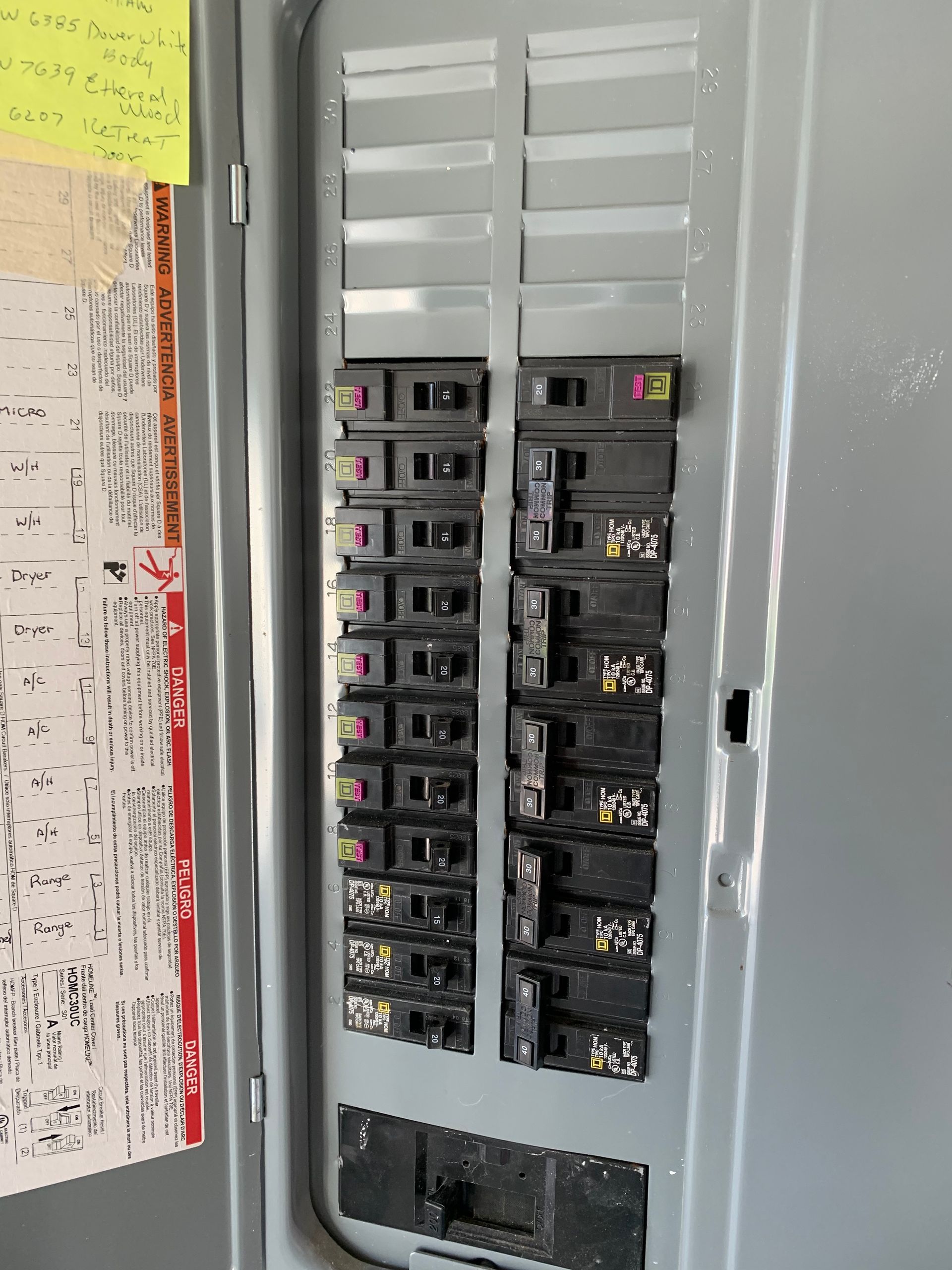 Open electrical breaker panel with rows of switches in a gray wall cabinet
