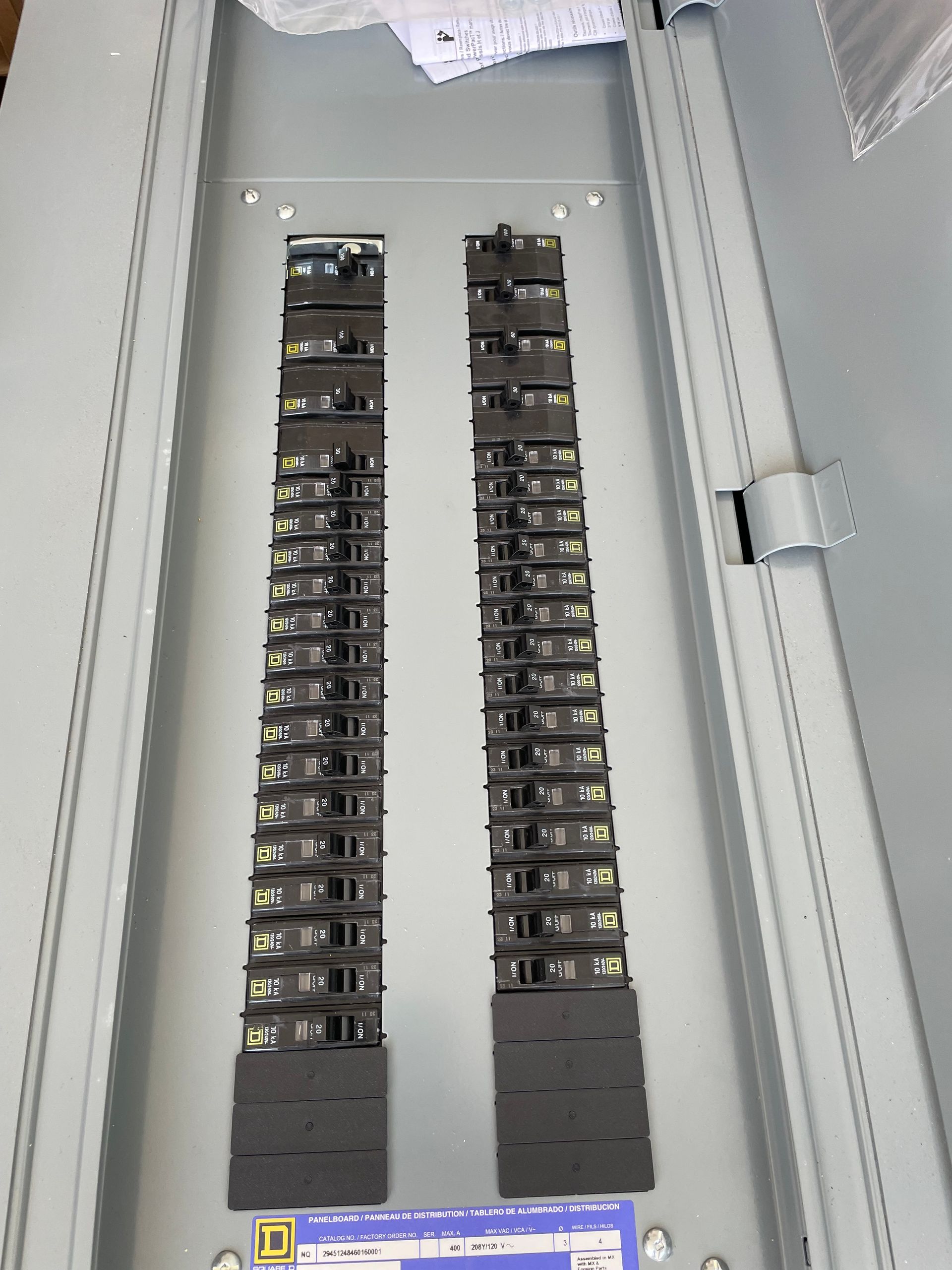 Open electrical breaker panel with two rows of circuit breakers and a few yellow labels inside.