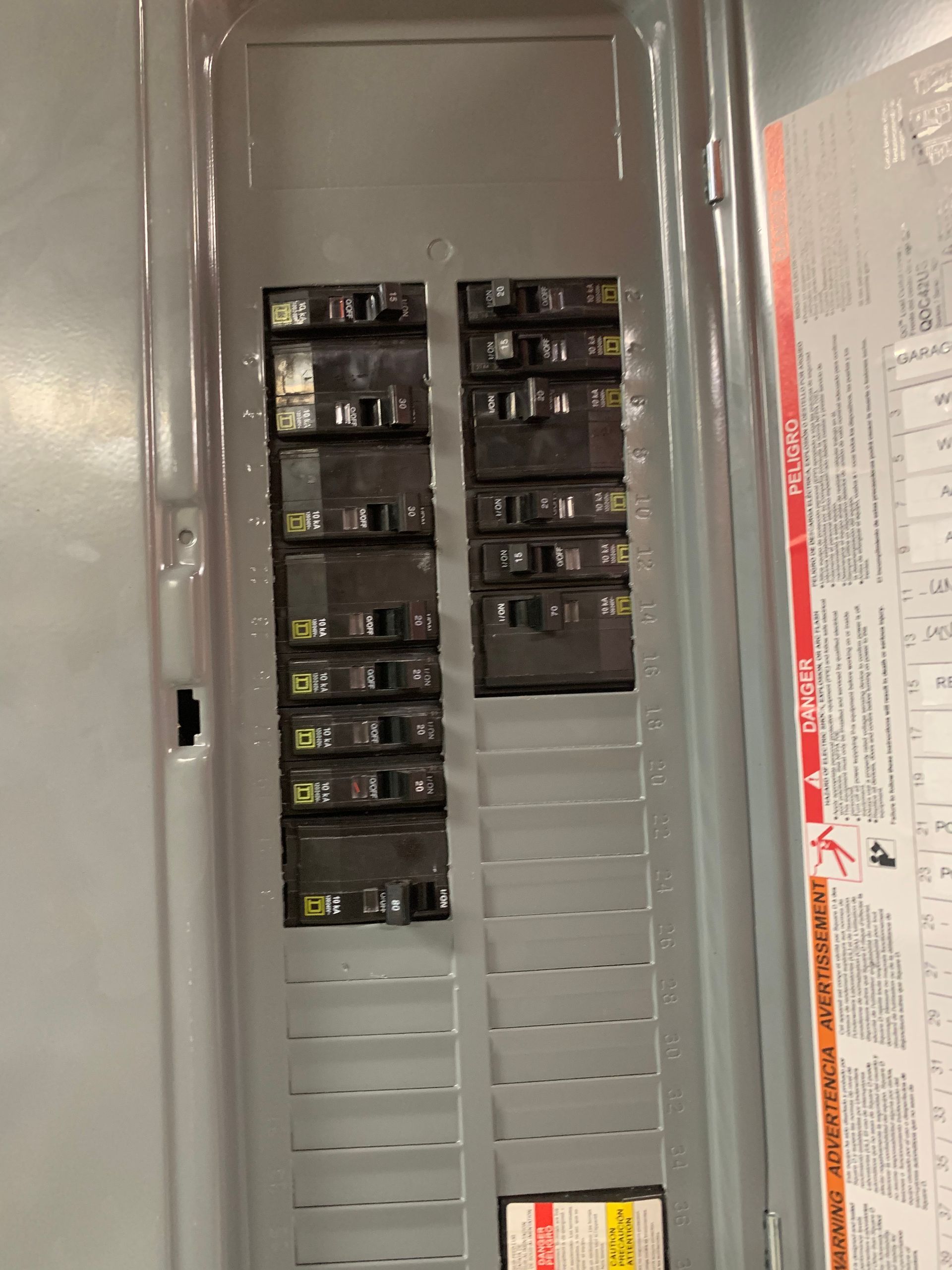 Electrical panel with rows of circuit breakers and a few labeled switches