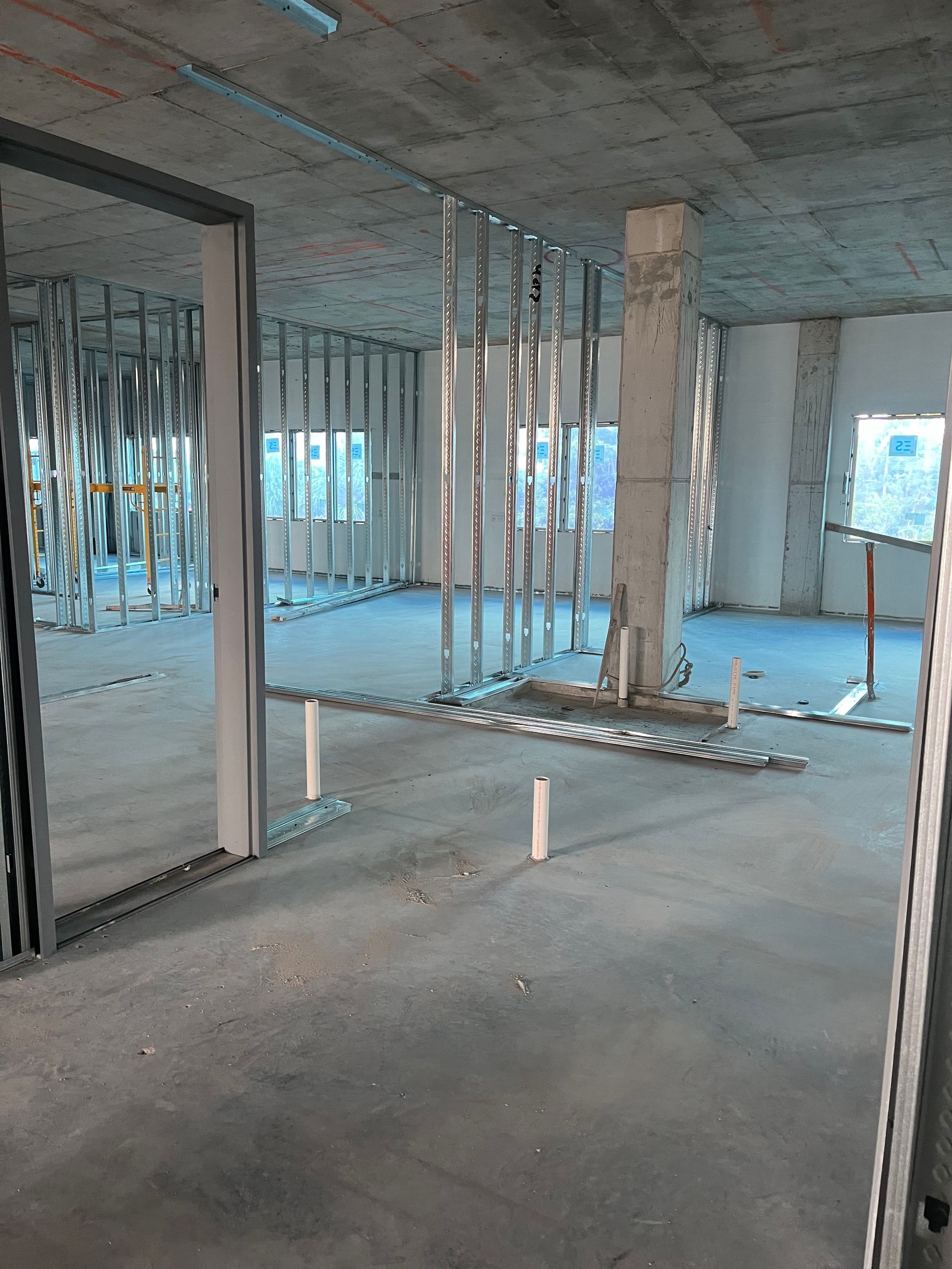 Empty unfinished room with exposed studs, concrete floor, and a central support column under construction