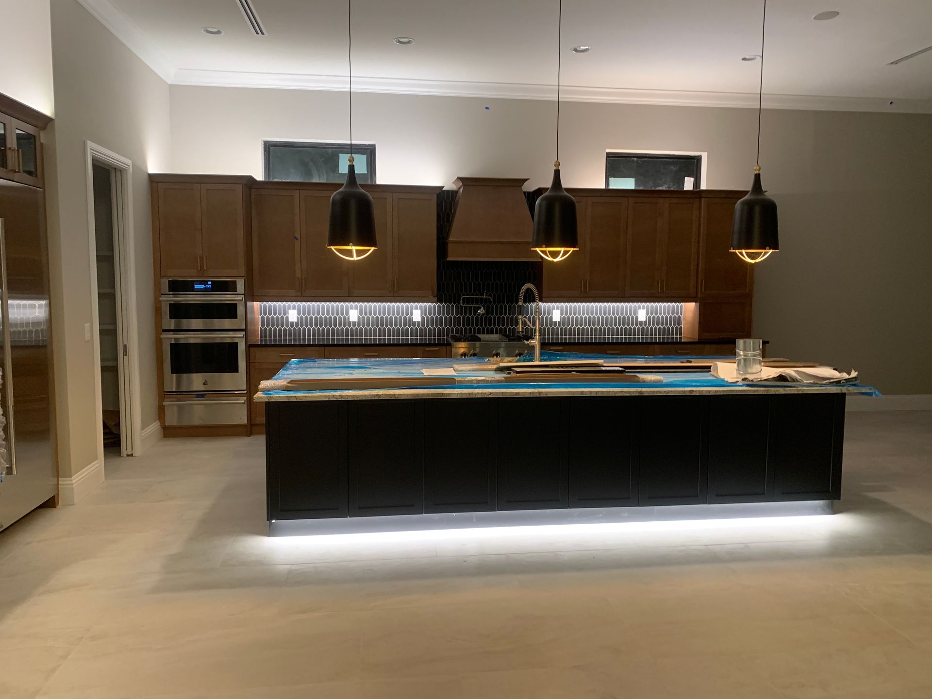 Modern kitchen with dark cabinets, central island, pendant lights, and built-in stainless appliances