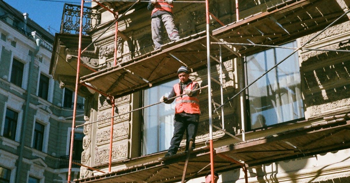 A man is standing on a scaffolding on the side of a building.