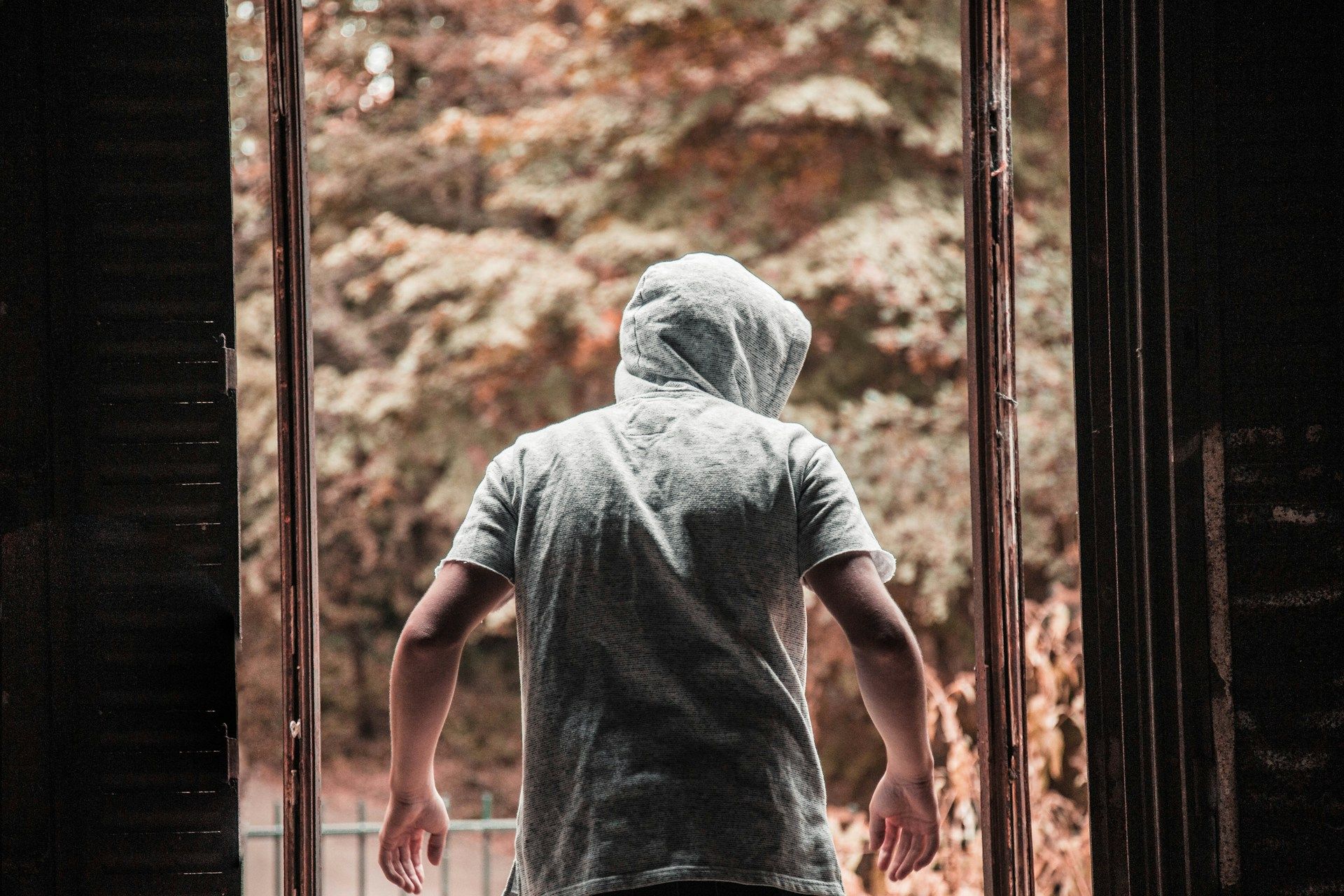 A man exiting a building in a grey hoodie