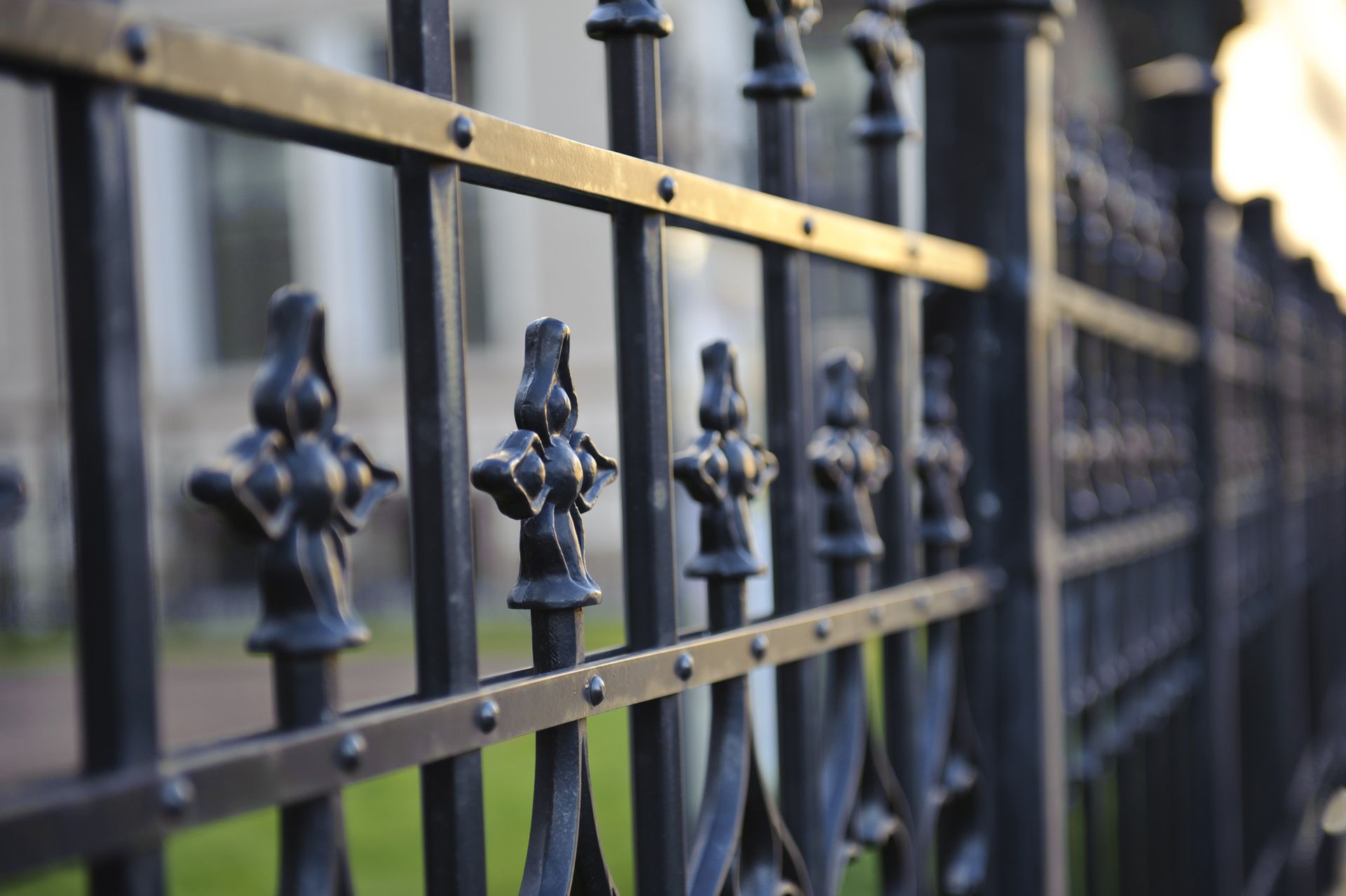 a close up of a wrought iron fence with a building in the background .