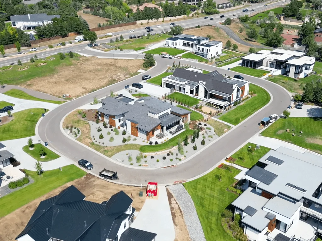 Aerial view of modern houses with dark roofs arranged along a winding road in a suburban neighborhood.