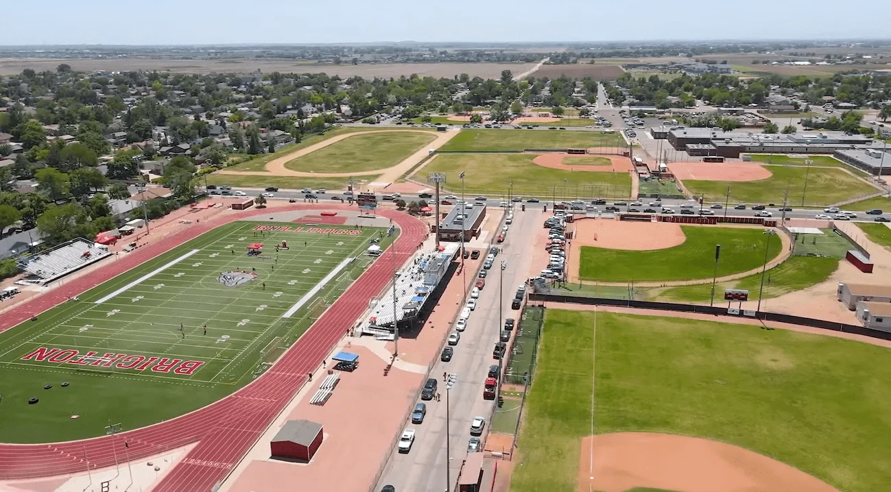 Aerial view of a sports complex featuring a football field with a running track and several baseball diamonds.