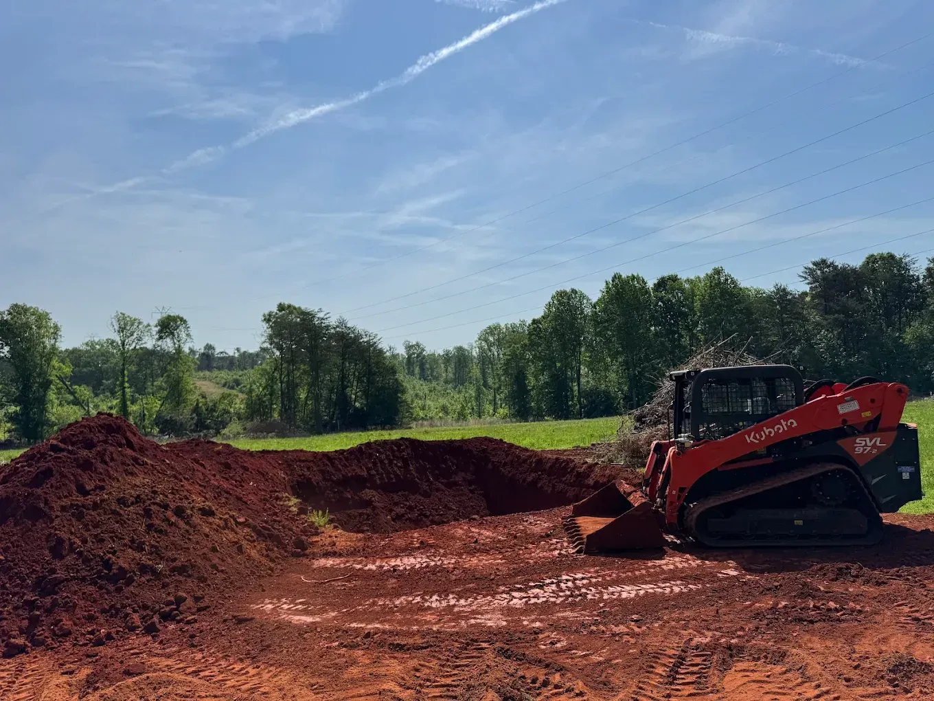 Red skid steer loading dirt on a sunny day.