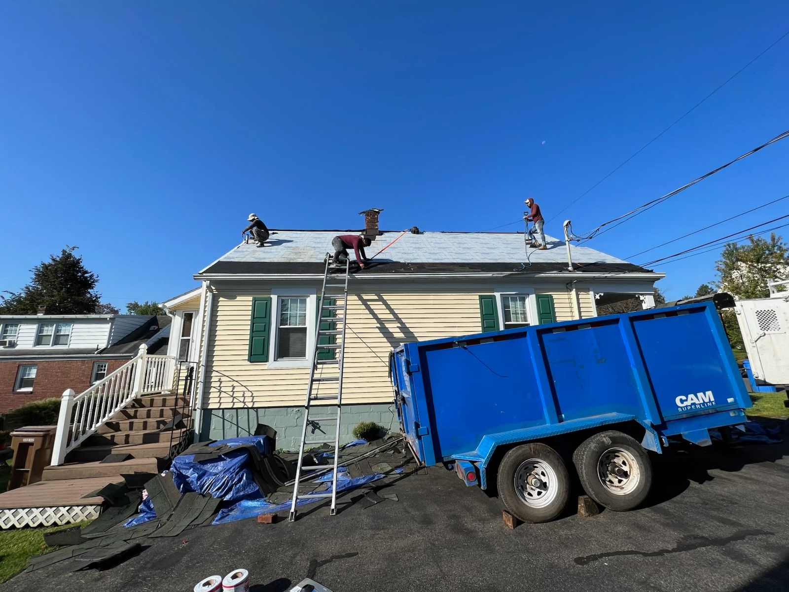 A blue dumpster is parked in front of a house.