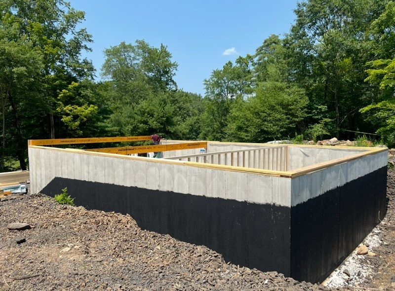 A large concrete wall is being built in the middle of a dirt field.