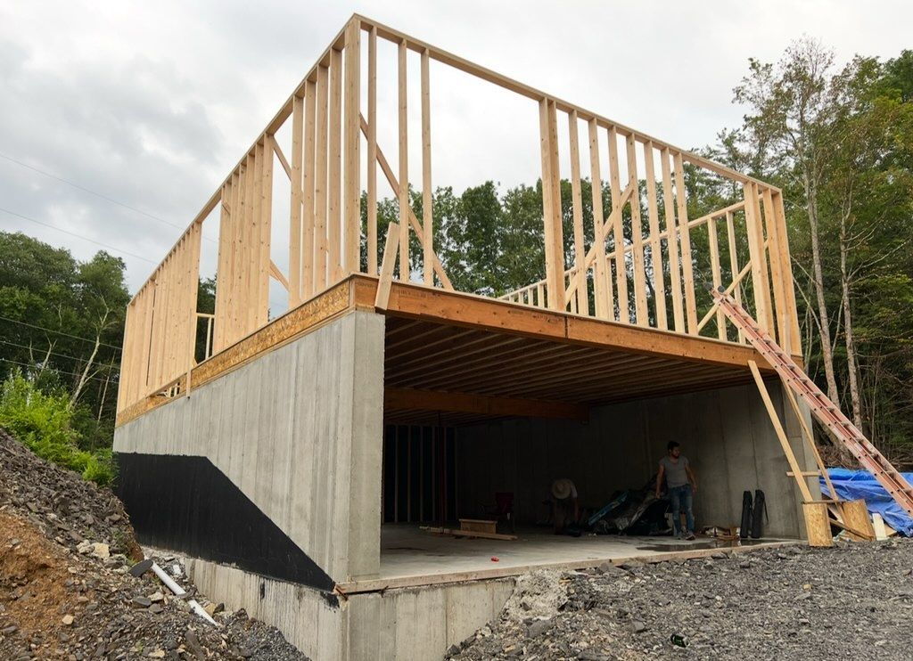 A house is being built with a concrete base and a wooden deck.