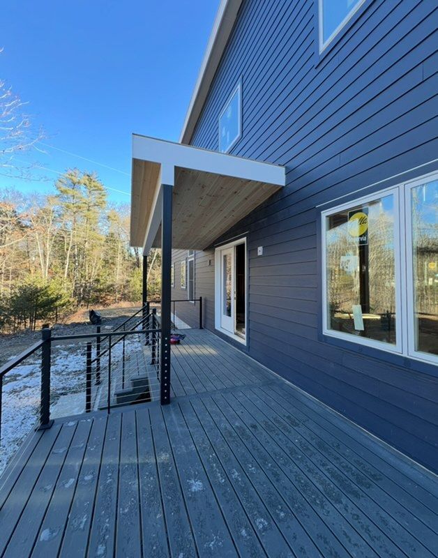 A large blue house with a large deck and stairs leading to it.
