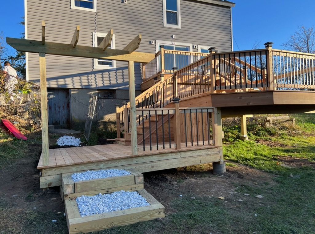 A wooden deck with stairs and a pergola in front of a house.