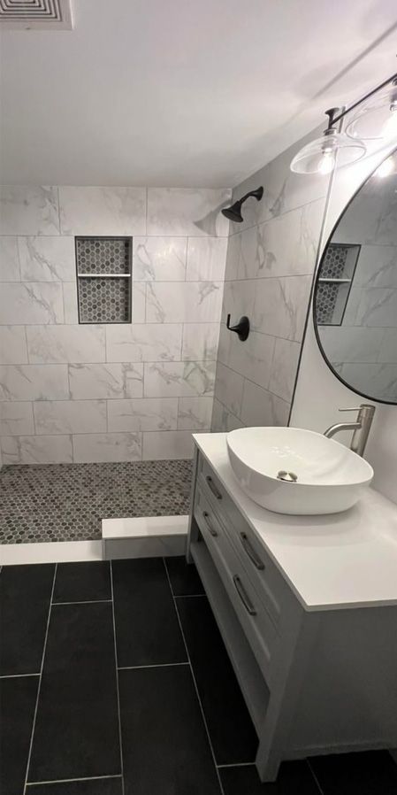 A bathroom with a sink , mirror and shower.