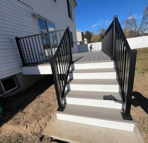 A deck with stairs leading up to it and a black railing.