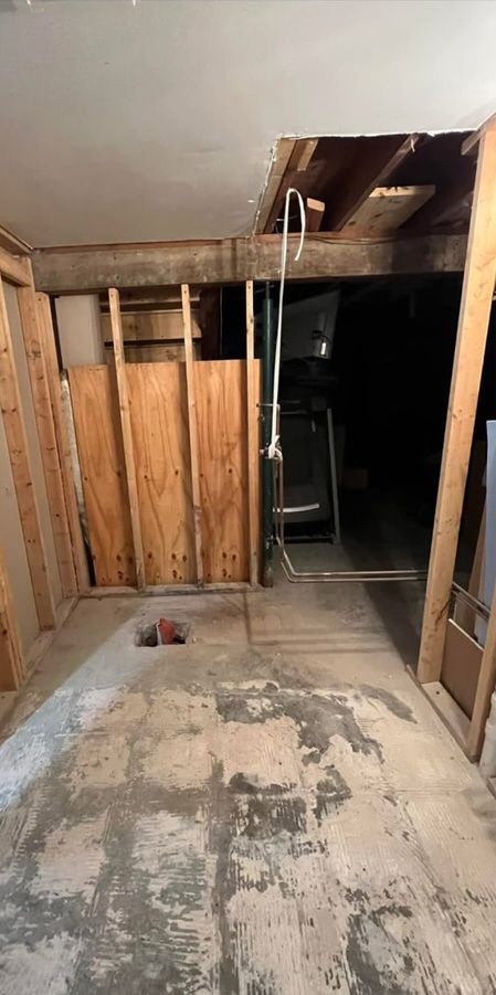 A basement with a hole in the floor and wooden walls.