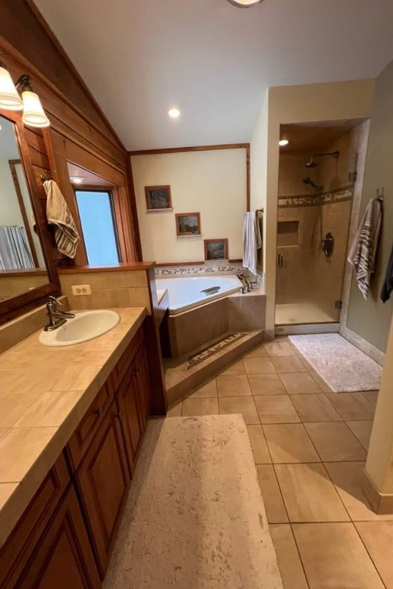 A bathroom with a sink , tub , shower and mirror.