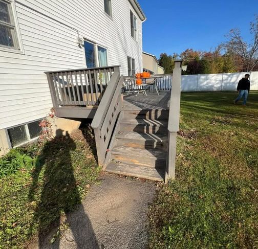 A wooden deck with stairs leading up to it in front of a house.
