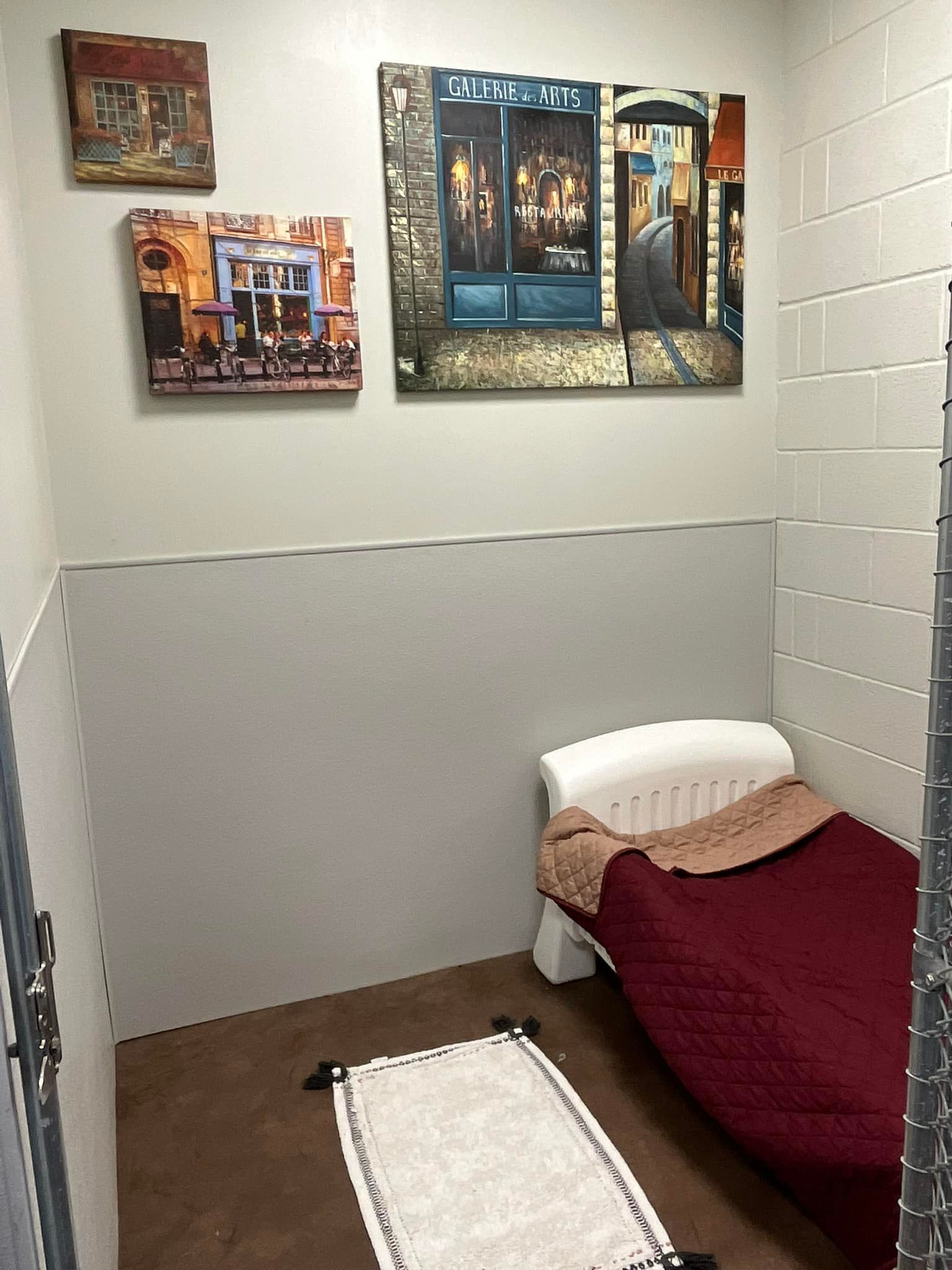 a small room with a bed and paintings on the wall