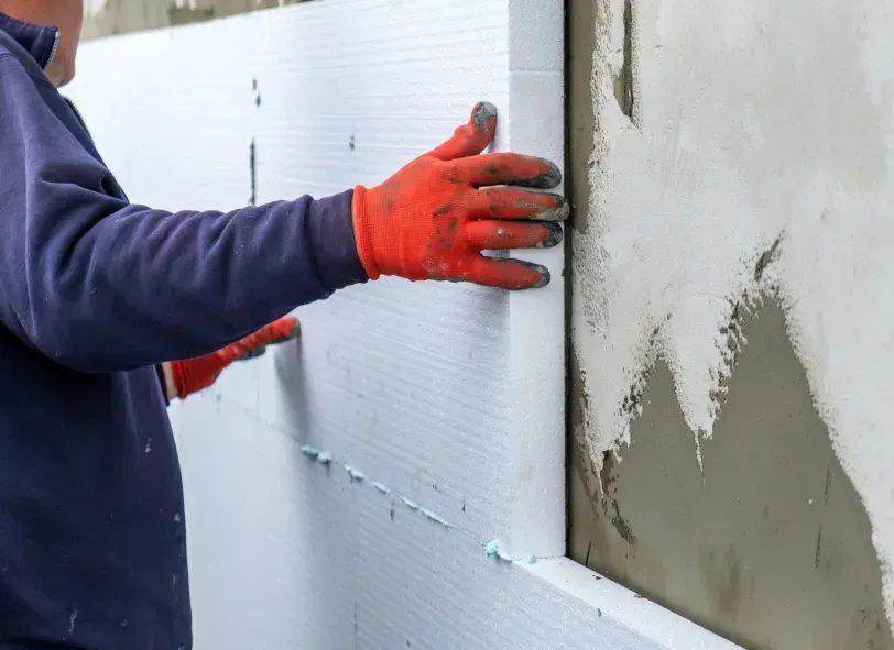 Un uomo che indossa guanti rossi sta lavorando su un muro.