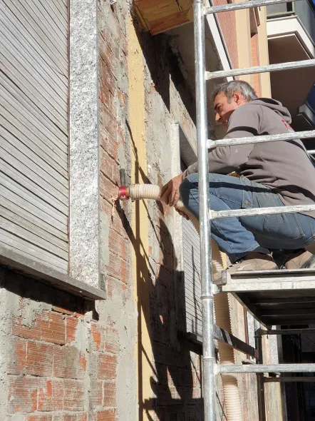 Un uomo è inginocchiato su un'impalcatura mentre lavora su un edificio.